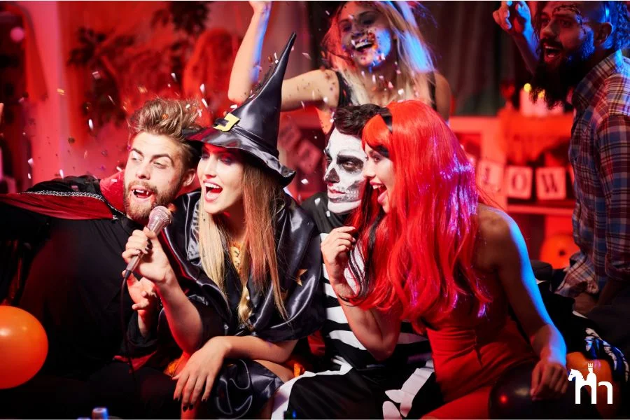 Freunde zu Halloween verkleidet mit Per&uuml;cken und geschminkten Gesichtern vor einem Mikrofon.