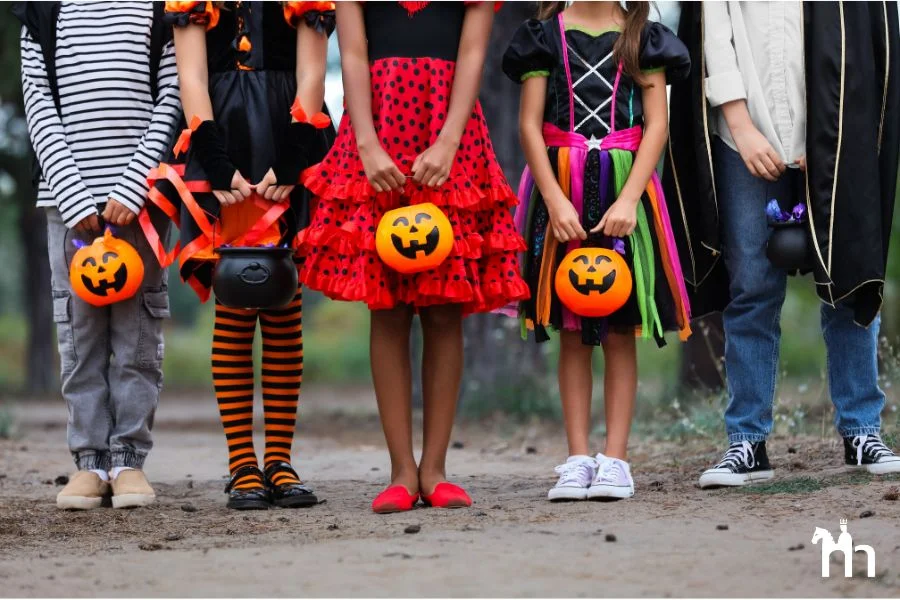 Verkleidete Kinder zu Halloween mit K&uuml;rbis-K&ouml;rben in der Hand, nebeneinander stehend.