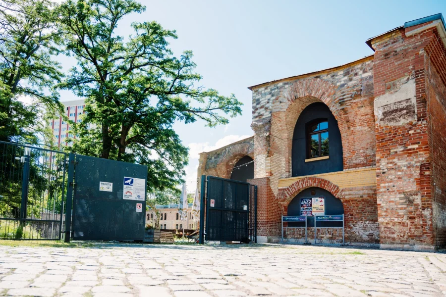 Eingang der Festung Mark: historische Backsteinfassade mit Rundbogenfenstern und Veranstaltungsplakaten, davor Kopfsteinpflaster und dunkles Metalltor