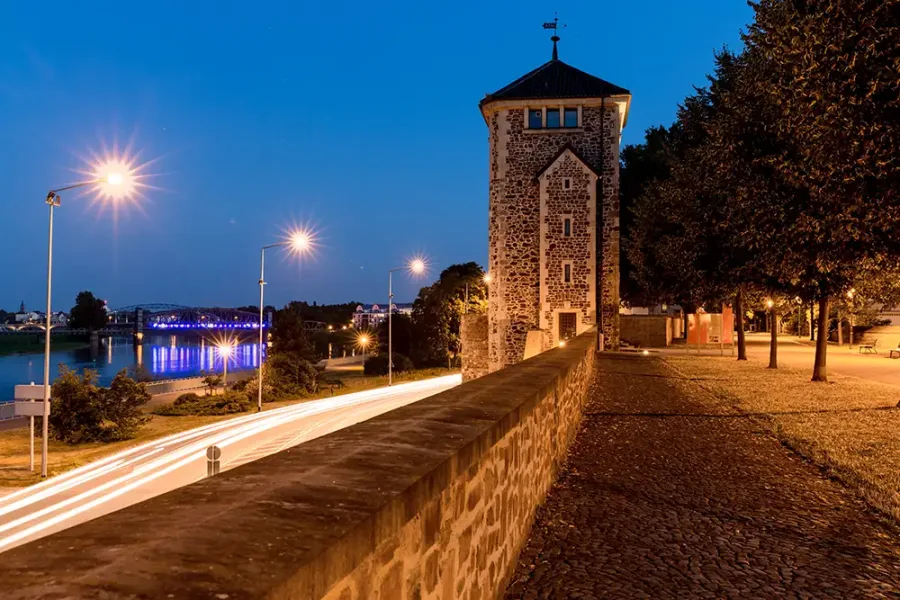 F&uuml;rstenwall bei Nacht mit einem Turm der alten Stadtbefestigung, Lichtspuren am Schleinufer und der blau beleuchteten Sternbr&uuml;cke &uuml;ber der Elbe