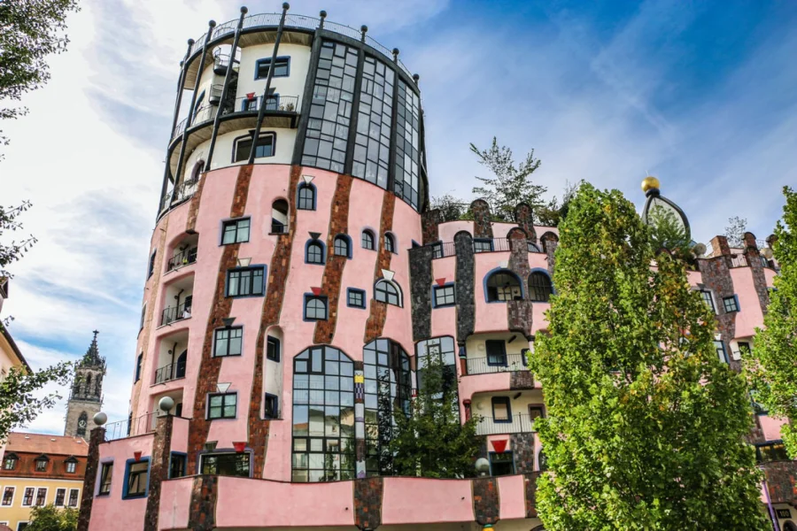 Rosa Fassade der Gr&uuml;nen Zitadelle mit unregelm&auml;&szlig;ig gesetzten Fenstern, gemauerten S&auml;ulen und dem gl&auml;sernen Turmaufbau