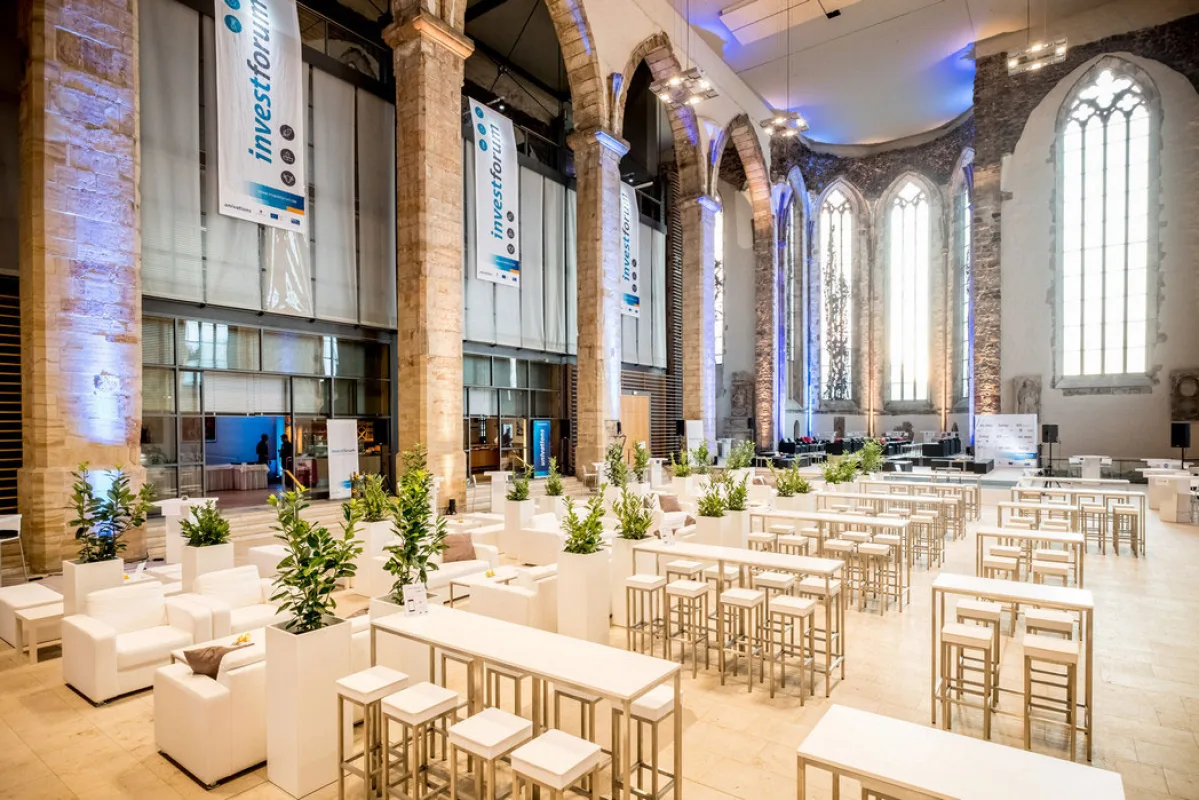 Empfang in der Johanniskirche mit wei&szlig;en Stehtischen, Loungem&ouml;beln und Veranstaltungsbannern zwischen den Sandsteins&auml;ulen