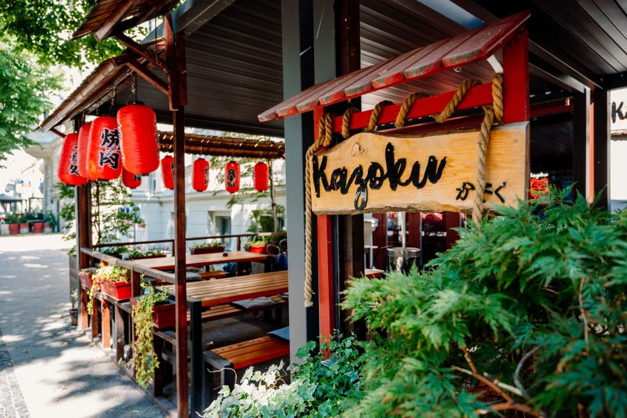 Blick auf den Eingangsbereich vom Kazoku Izakaya mit Sitzgelegenheiten aus Holz und roten Lampions