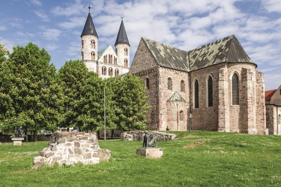 Klosterkirche Unser Lieben Frauen von Osten, davor die Wiese des Skulpturengartens mit Bronzefiguren, Mauerresten und bl&uuml;henden Kastanien