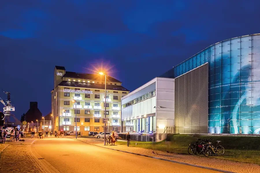 Abendstimmung im Wissenschaftshafen: die beleuchtete Denkfabrik und das blau schimmernde Technikmuseum-Rondell an der Hafenstrasse