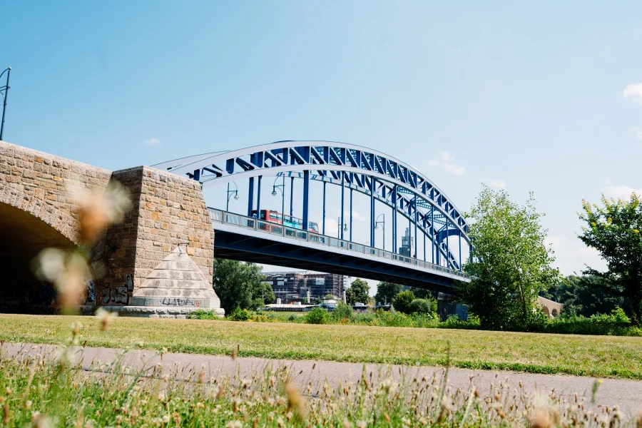 Sternbr&uuml;cke, auf der ein Doppeldeckerbus f&auml;hrt. Blauer Himmel im Hintergrund und Gr&auml;ser im Vordergrund.