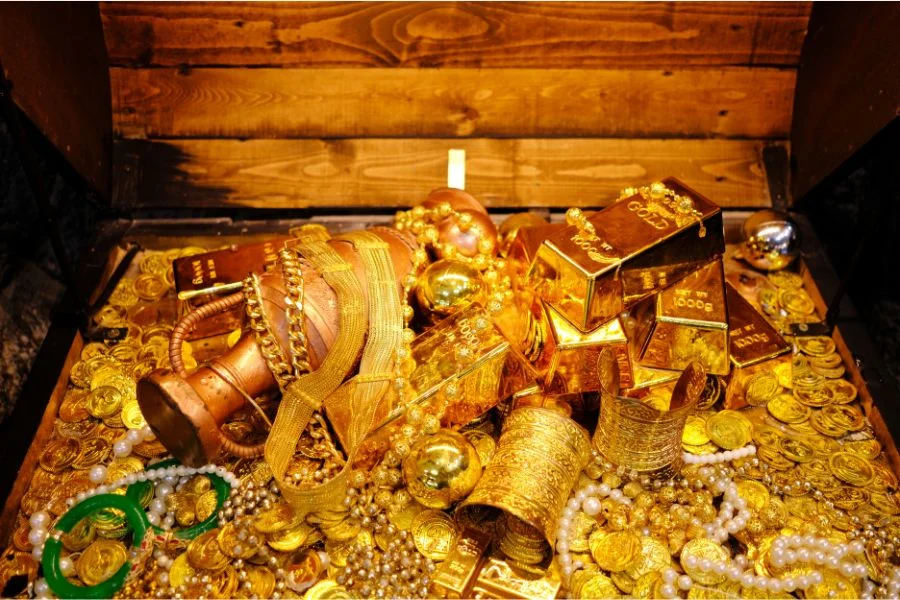 Blick in eine Schatztruhe mit Goldtalern, Schmuck, Kr&uuml;gen und Diamanten.