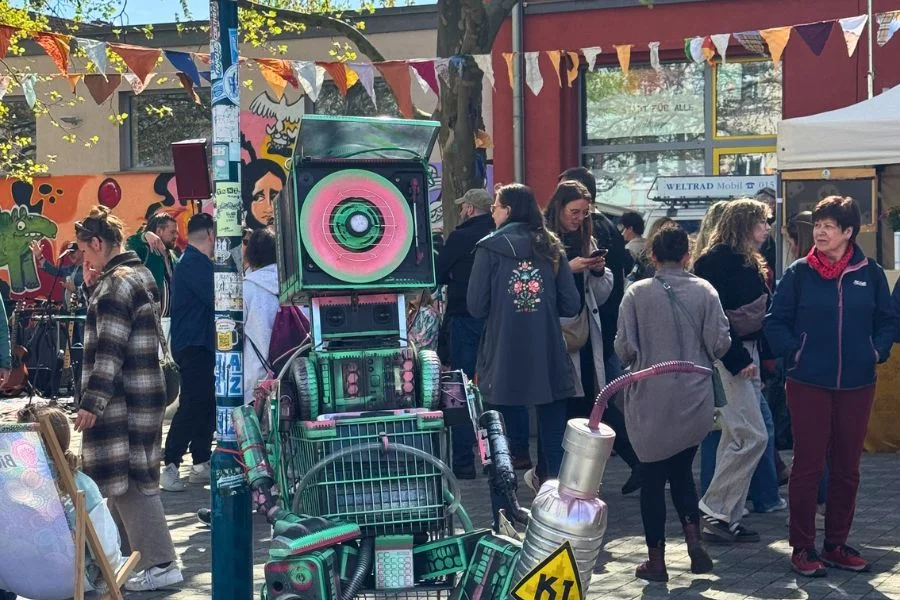 Mehrere Menschen auf dem Thiemmarkt in Buckau, im Vordergrund ein selbstgebauter Roboter. &Uuml;ber der Stra&szlig;e h&auml;ngen Girlanden.